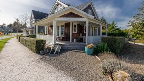 Een tweelaags huis met een overdekte veranda, een grindpad en een verzorgde tuin.