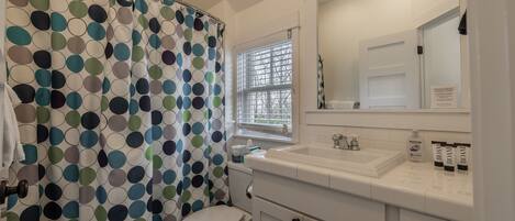 A bathroom with a toilet, a sink, and a shower curtain with a polka dot pattern.