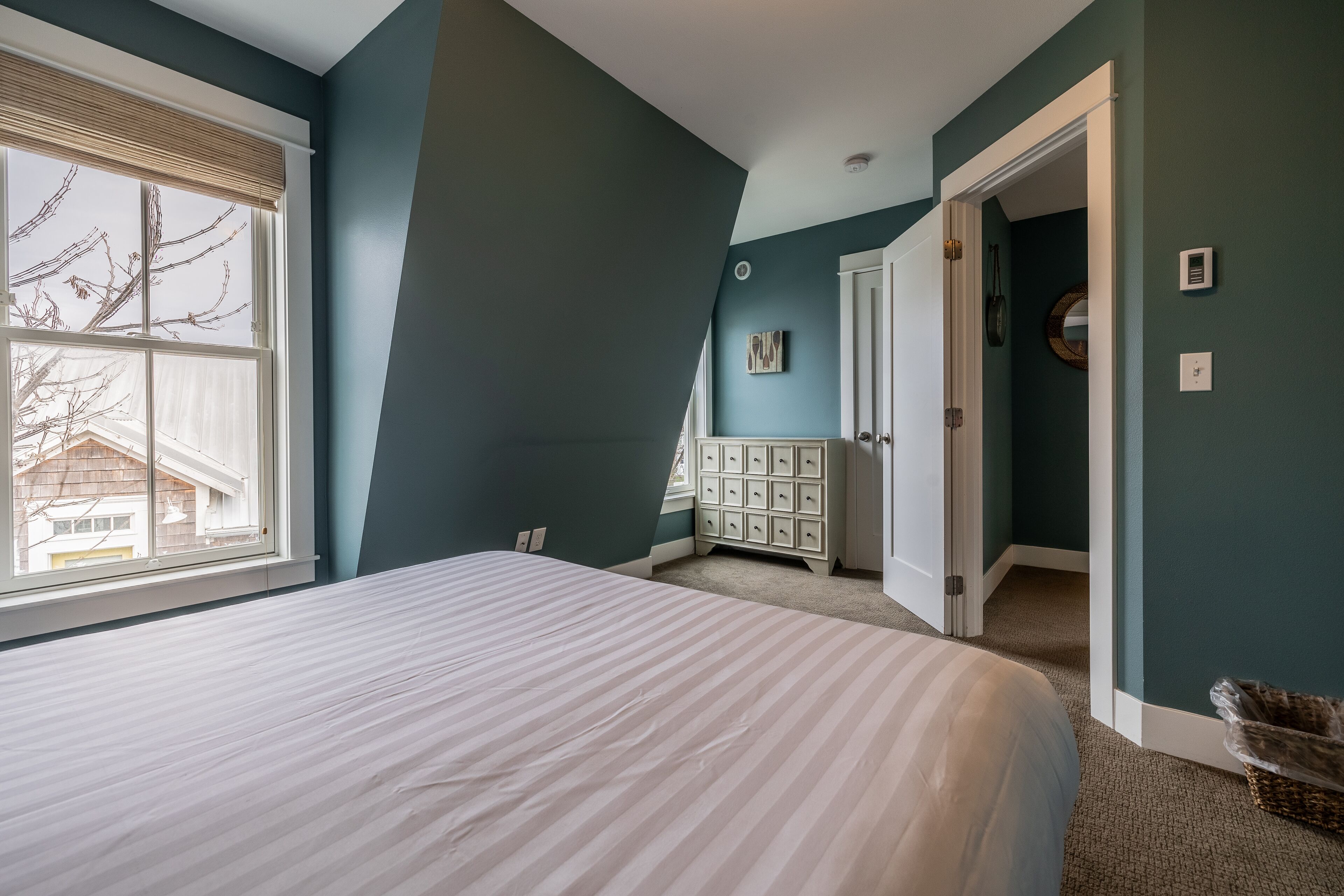 A bedroom with a large bed, a dresser, and a walk-in closet.