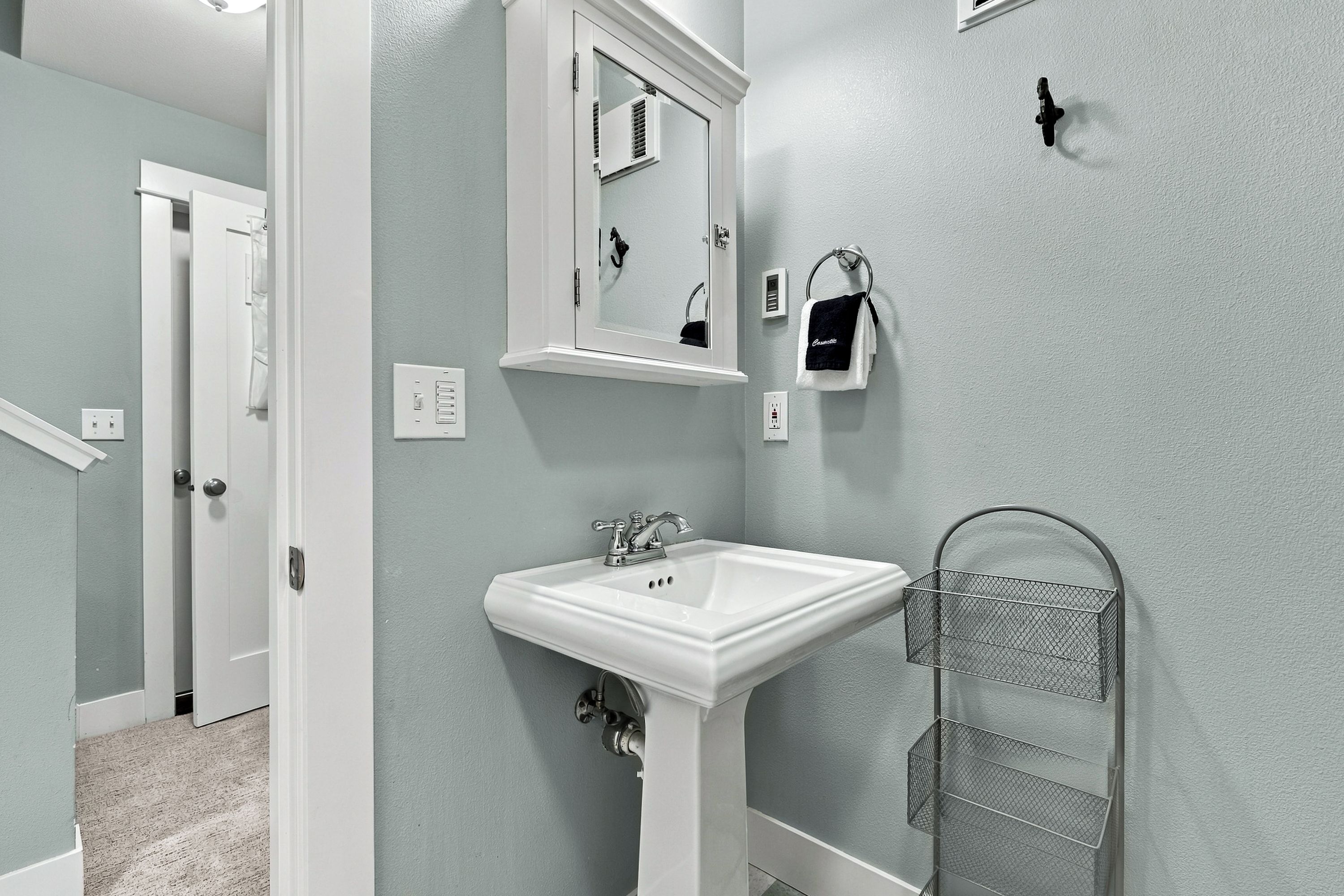 A bathroom with a white sink, a mirror, a towel rack, and a shower area.