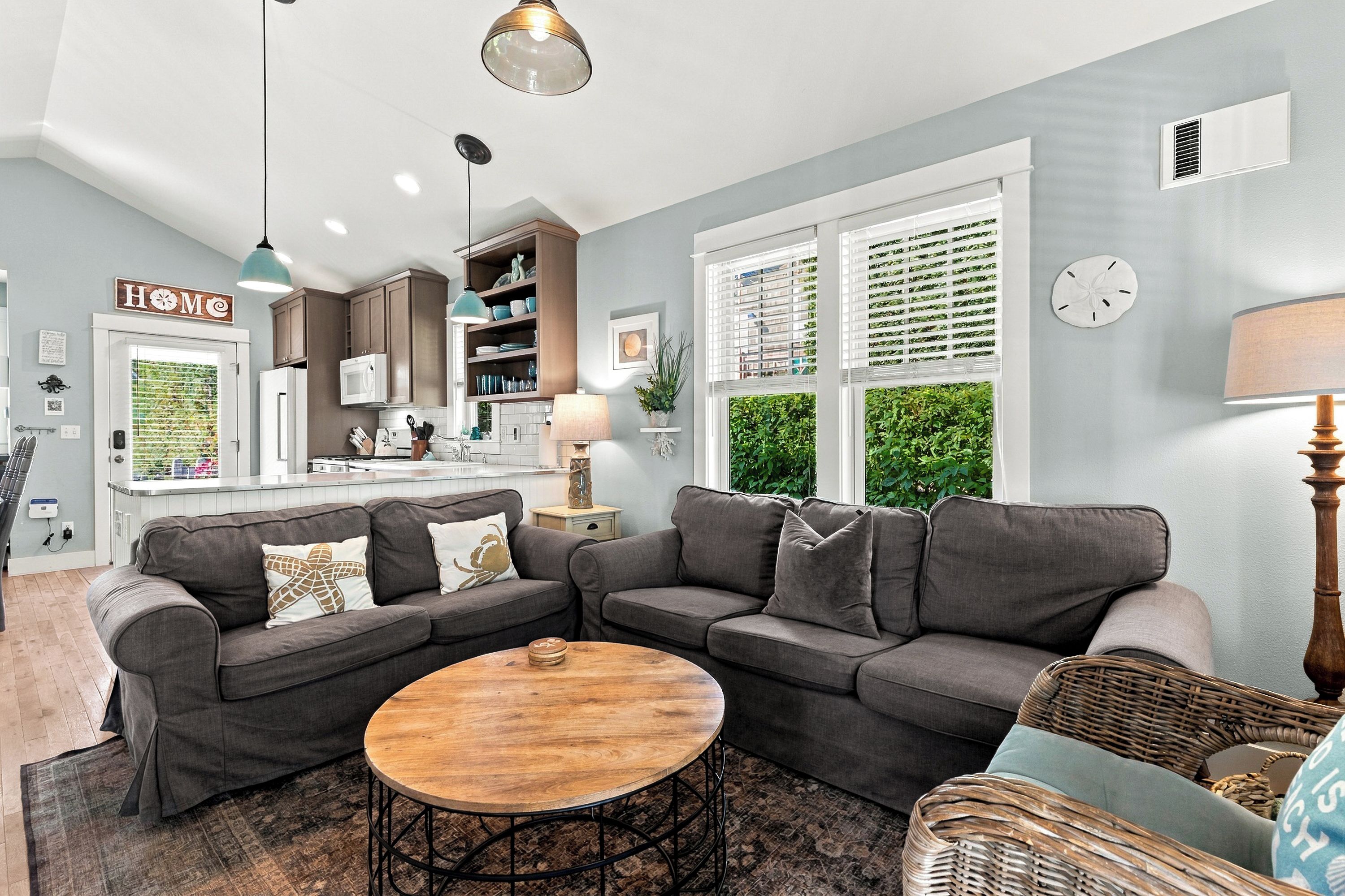 Un soggiorno moderno con un divano componibile, un tavolino rotondo e una poltrona in vimini.