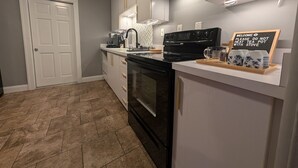 Een moderne keuken met een zwart fornuis, witte kastjes en een bordje op het aanrecht.