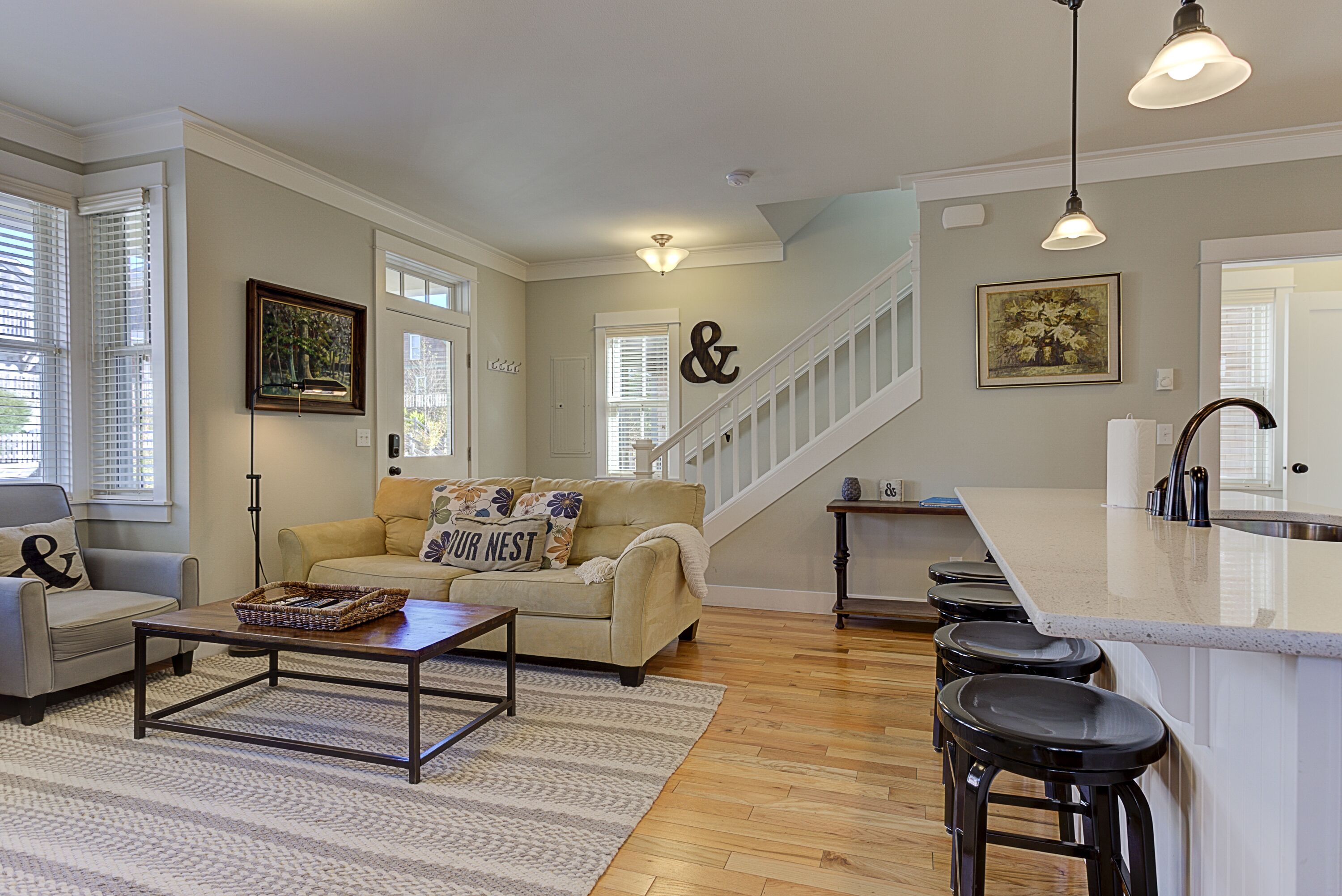 A spacious living room with a sofa, coffee table, and a staircase leading to an upper level.