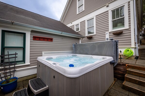 Ein Whirlpool in einem Hinterhof mit einer Holzterrasse und einem Haus im Hintergrund.