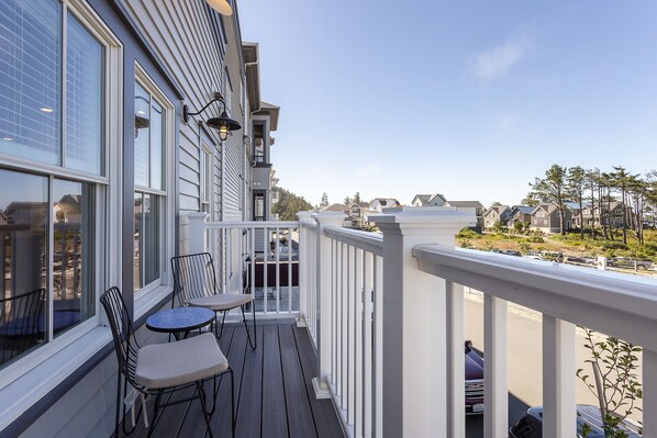 A balcony with a white railing, two chairs, and a small table. - Seabrook's At Last, a loft in Town Center! (Pacific Beach)