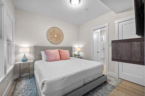 A bedroom with a bed, bedside lamps, a decorative wall piece, and a wardrobe. - Seabrook's At Last, a loft in Town Center! (Pacific Beach)