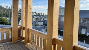 A wooden deck with a view of residential buildings and a forested area. - Seabrook Aurum Hues | Ocean View, Hot Tub, Pet Friendly, 4BR, Sleeps 10 (Pacific Beach)