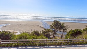 Une plage avec une clôture en bois au premier plan et une vue dégagée sur l’océan.