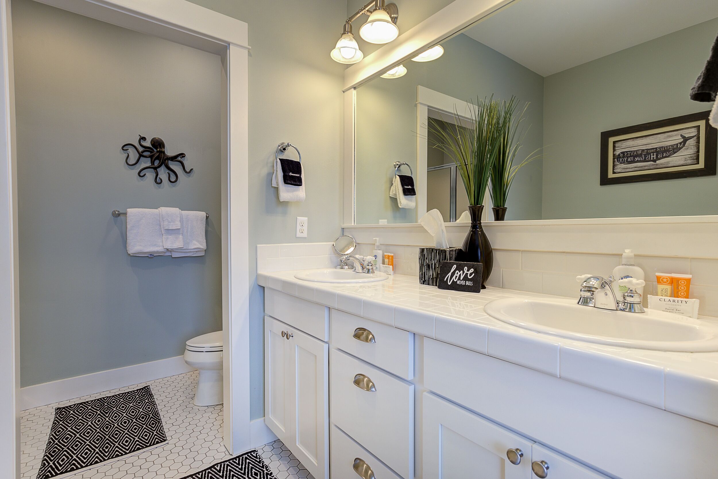 A modern bathroom with two sinks, a large mirror, and a towel rack.