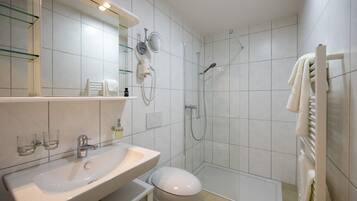 Un baño moderno con lavamanos blanco, espejo y cabina de ducha de vidrio.