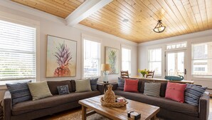 Ein gemütliches Wohnzimmer mit Holzbalkendecke, zwei Sofas mit verschiedenen Kissen, einem Couchtisch und Bildern an den Wänden.