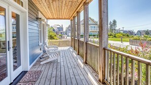 Eine Holzterrasse mit überdachter Veranda, einer Glasschiebetür und Blick auf Nachbarhäuser.