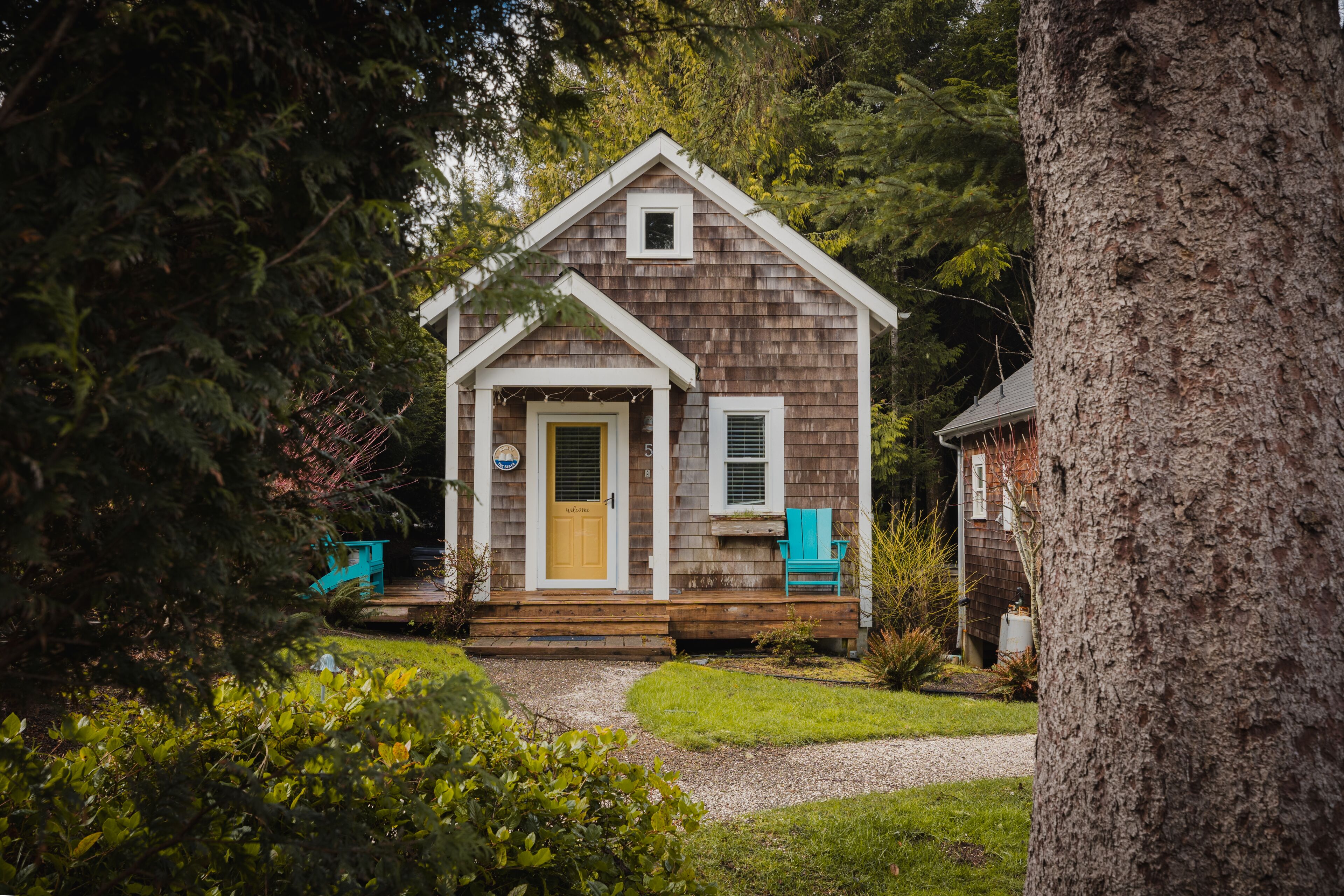 A small wooden house with a front porch, a door, and a window.