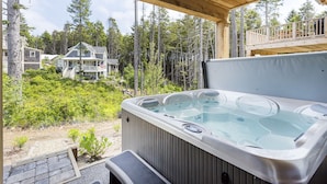 A hot tub under a wooden deck with a view of a house and forest. - Seabrook Buoyed by Love | Hot Tub, Town Green Park | 3BR, Sleeps 8, Conservation (Pacific Beach)