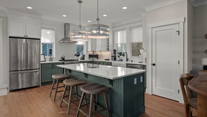 A modern kitchen with a central island, stainless steel appliances, and pendant lighting. - Seabrook's CaberNeigh Getaway, a 3-story home in South Farm! (Pacific Beach)