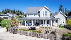 Une grande maison à deux étages dotée d’un porche couvert, d’un barbecue et d’une cour clôturée.