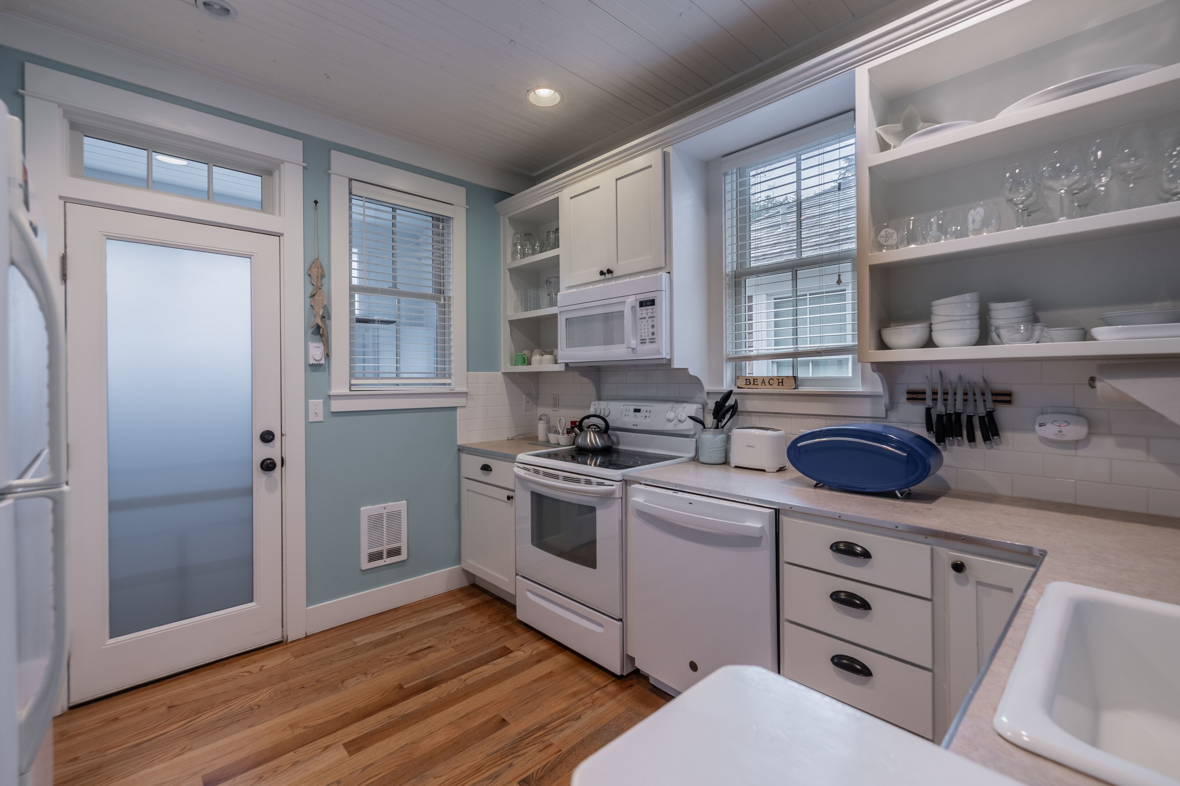 A compact kitchen with white cabinetry, a microwave, a stove, and a dishwasher.