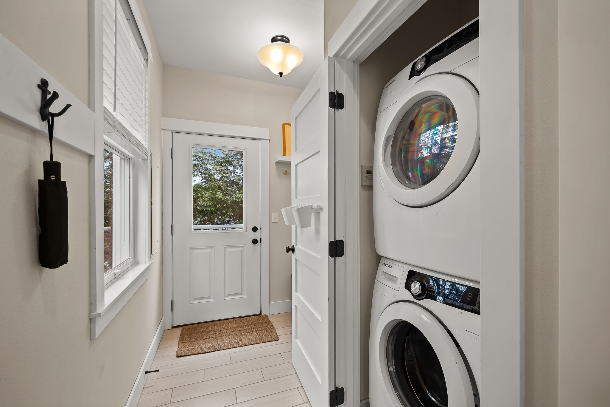 A laundry room with a washing machine, a drying rack, and a door leading to a balcony.