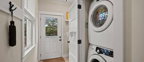 A laundry room with a washing machine, a drying rack, and a door leading to a balcony.