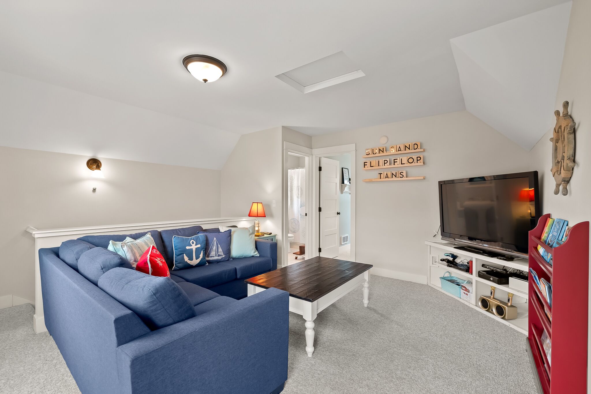A living room with a blue sofa, a coffee table, a TV, and a bookshelf.