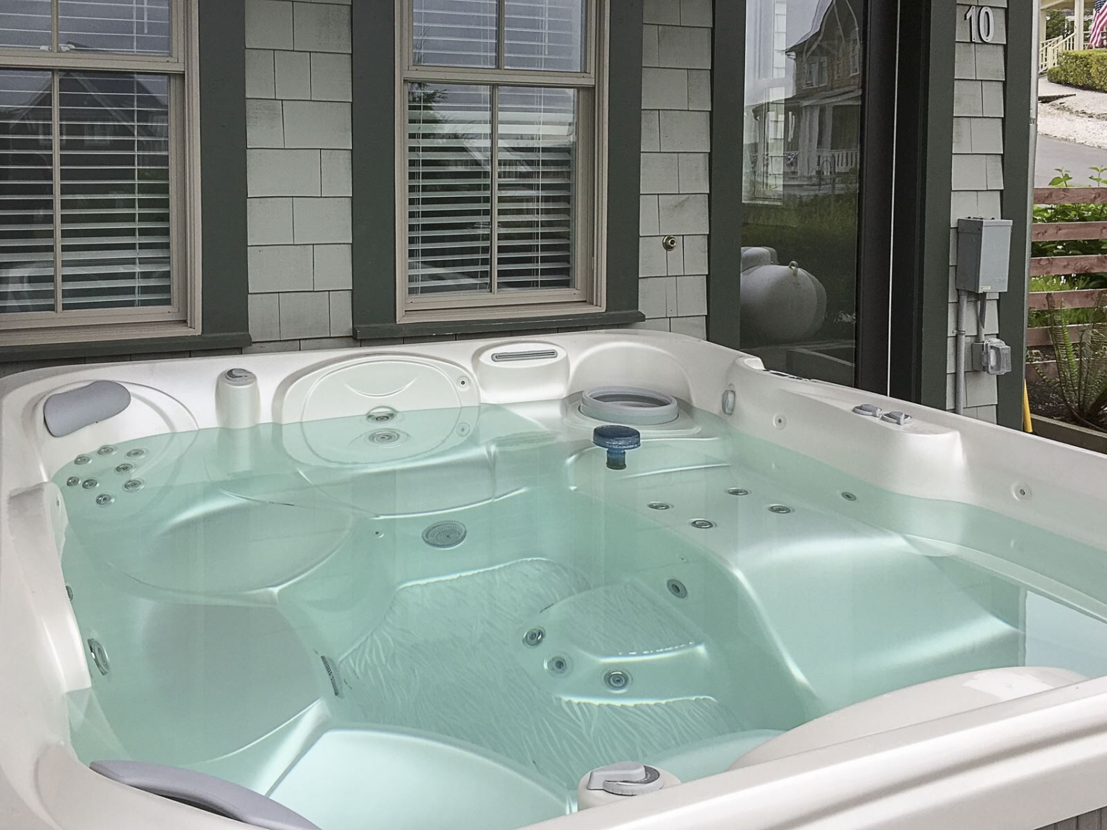 A hot tub with a glass cover, a control panel, and a door with a glass panel.