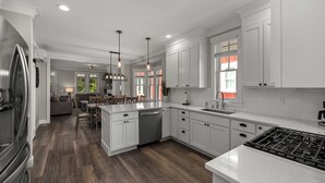 A modern kitchen with white cabinetry, a stainless steel refrigerator, and a central island with seating. - *NEW* Coastal Oasis, Hot Tub! (Pacific Beach)