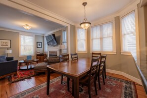 A dining area with a wooden table and chairs, a fireplace, and a television mounted on the wall.