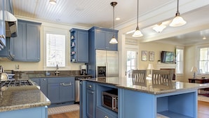 A kitchen with blue cabinets, stainless steel appliances, granite countertops, and pendant lighting. - Seabrook Crew Rest | Ping Pong, Carriage House 4BR | Sleeps 12, Crescent Park (Pacific Beach)