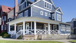 A two-story house with a covered porch and a picket fence.