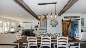A spacious dining area with a wooden table and white chairs, a fireplace, and a sign reading "FARMER'S MARKET".