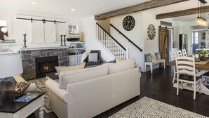 A spacious living room with a fireplace, a dining area with a wooden table and chairs, and a staircase leading to another level.