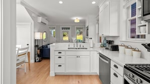 A modern kitchen with white cabinetry, a central island, a stove, and a sink. - Seabrook Dune Our Thing | Pet Friendly, Hot Tub | 2BR, Sleeps 4, Farm District (Pacific Beach)