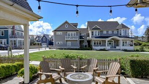 A patio with Adirondack chairs and a fire pit, overlooking a row of houses. - Seabrook Eagles Nest | Ocean View, Hot Tub | 5BR, Sleeps 14, West Hill Park (Pacific Beach)