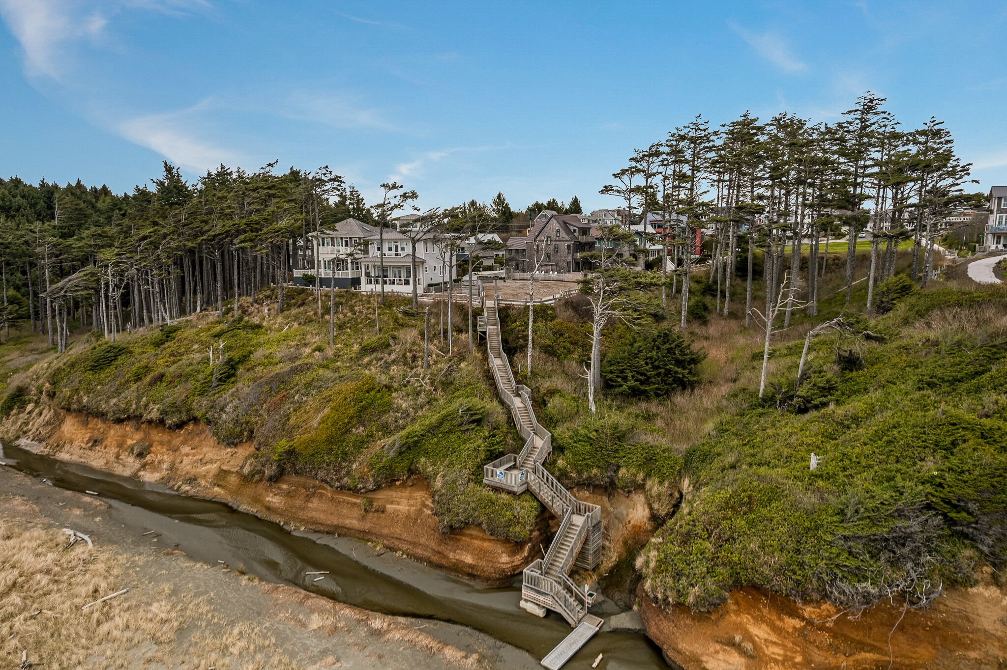 A coastal residential area with houses, a winding pathway, and a river.