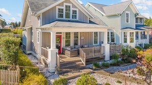 A two-story house with a porch, a red door, and a well-maintained garden.
