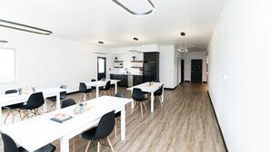 A modern office space with white tables, black chairs, and a kitchen area. - Conestoga Quarters (Jefferson City)
