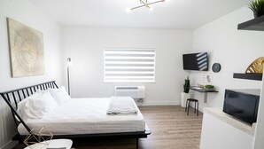A modern bedroom with a bed, bedside table, and a TV. - Conestoga Quarters (Jefferson City)