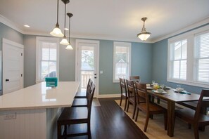 A kitchen with a central island, wooden chairs, and a dining table set for four. - Seabrook Hannah's Haven | Hot Tub, Family, 3BR | Sleeps 8, Gnome Trail, Mill Dis (Pacific Beach)