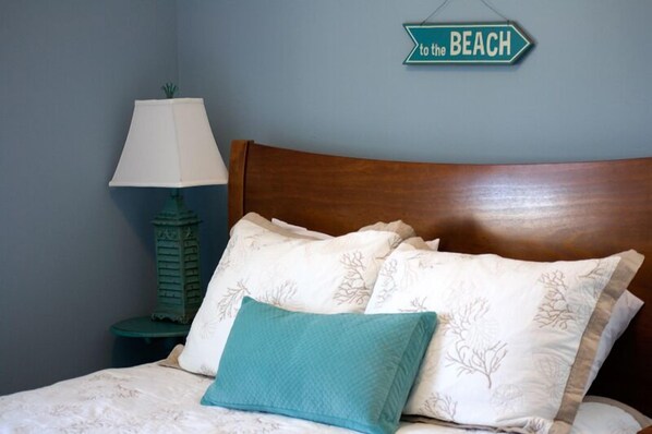 A neatly made bed with a wooden headboard, a lamp, and a wall sign that reads "to the BEACH". - Seabrook Hannah's Haven | Hot Tub, Family, 3BR | Sleeps 8, Gnome Trail, Mill Dis (Pacific Beach)