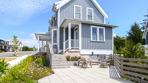 Une maison à deux étages avec un porche, un escalier menant à la porte d’entrée et un espace salon extérieur.