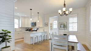 A spacious kitchen with white cabinetry, a central island with stools, and a dining area with a bench.