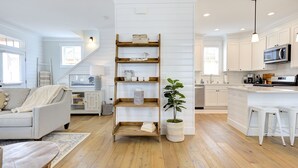 A modern kitchen with white cabinetry, wooden shelves, and a potted plant.
