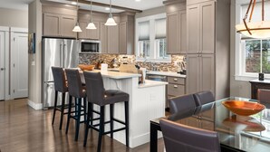 Una cucina moderna con isola centrale, sgabelli da bar e illuminazione a sospensione.