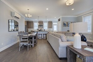 Eine geräumige Küche mit Holzausstattung, ein Essbereich mit Holztisch und -stühlen sowie ein Wohnbereich mit Sofa und Couchtisch.