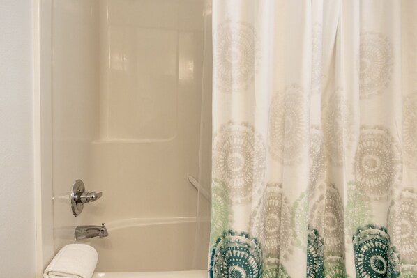 Ein Badezimmer mit Badewanne, Toilette und einer Duschvorhang mit Muster.