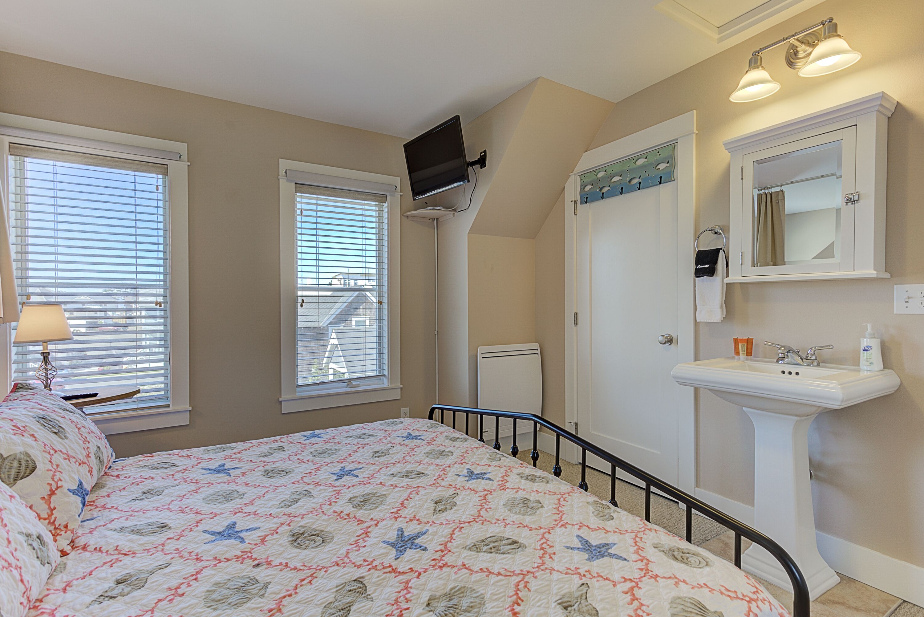 A bedroom with a bed, a window, a radiator, a sink, and a mirror.