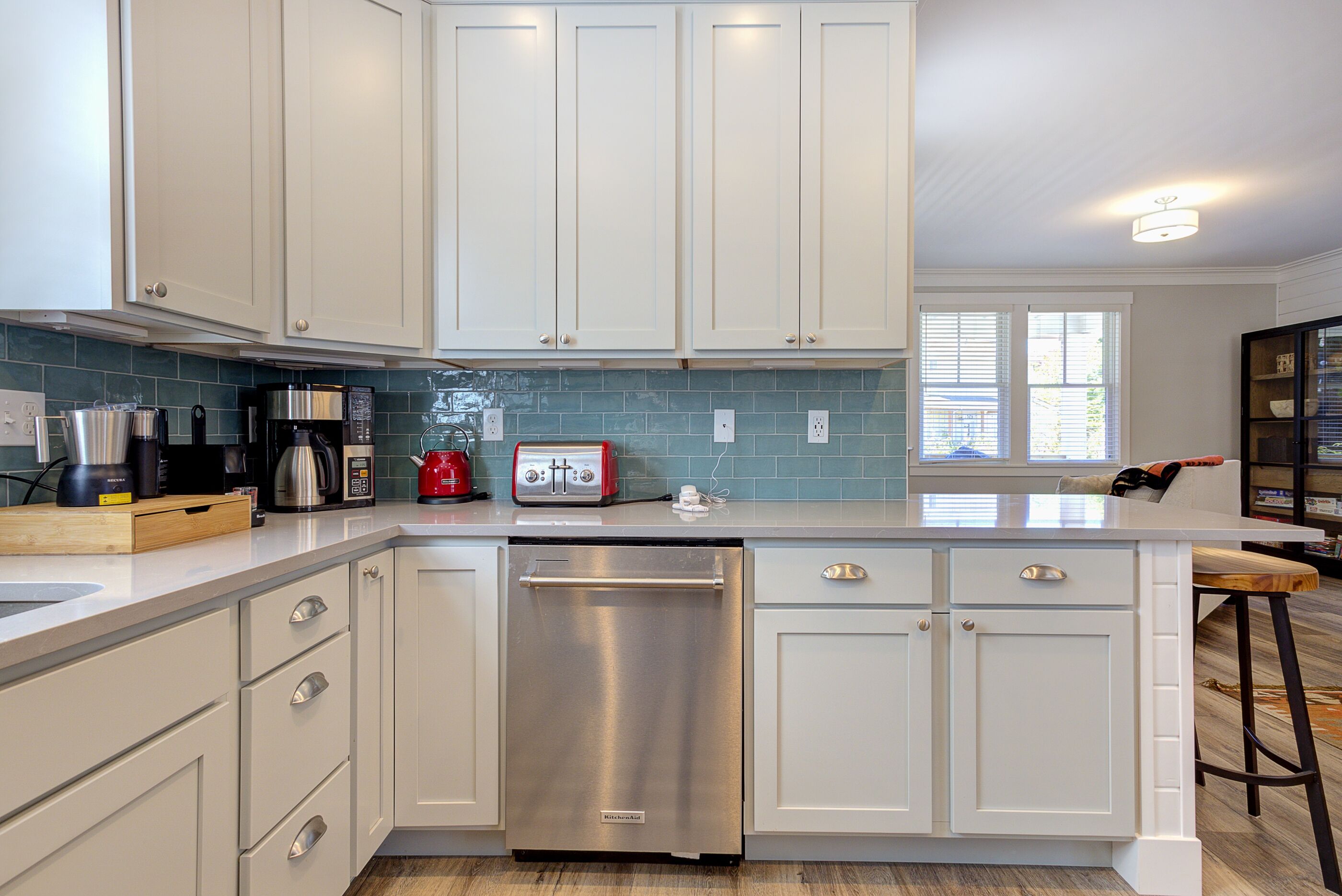 A modern kitchen with white cabinets, stainless steel appliances, and a blue-tiled backsplash.