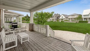 A covered outdoor deck with white chairs and a grill, overlooking a well-maintained lawn and neighboring houses. - *NEW* Seabrook's Junebug, Hot Tub, Fenced Back Yard, Now Dog Friendly! (Pacific Beach)