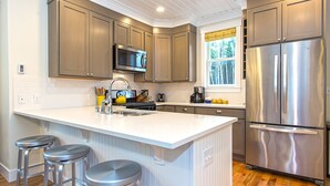 A modern kitchen with a large island, stainless steel appliances, and wooden flooring. - *NEW* Seabrook's Junebug, Hot Tub, Fenced Back Yard, Now Dog Friendly! (Pacific Beach)