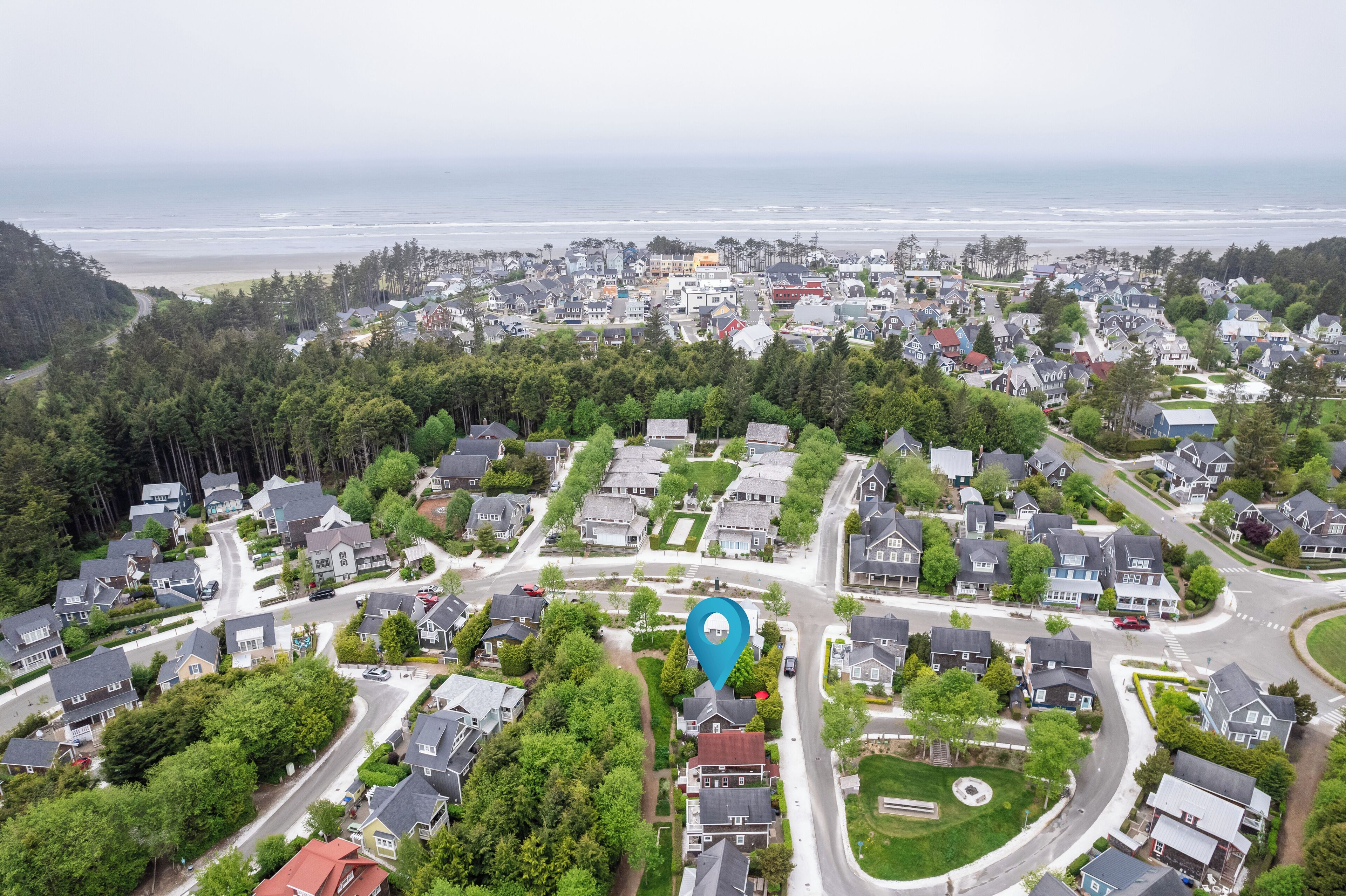 An aerial view of a residential area with houses, roads, and a beach in the background.